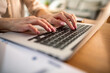© Davor - Close-up of woman's hands typing on laptop at home