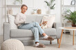 © Pixel-Shot - Beautiful woman in soft slippers with cat using laptop on sofa at home