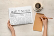 © Pixel-Shot - Female hands with newspaper writing down something on white background. Top view