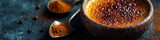 A close-up of a creme brûlée with caramelized sugar and spoons of spice on a dark background