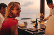 © Jacob Lund - Smiling woman enjoying a gourmet dining experience at sunset restaurant