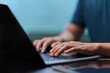© Antony Weerut - Close-up of hands typing on a laptop keyboard. Concept for business, remote work, programming, or freelance lifestyle. Man working with modern technology in an office or home environment. Searching.