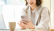 © Trickster* - スマートフォンを見る笑顔のビジネスウーマン, Smiling Businesswoman Using Smartphone at Desk