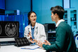 © Nuttapong punna - Female doctor examining male patient with stethoscope in hospital. Brain MRI scan on screen, medical diagnosis, healthcare consultation and modern medical technology.
