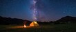 © TheWaterMeloonProjec - Horizontal image of a lit tent and campfire under a breathtaking star-filled sky, mountain summer night, astrophotography, copy space