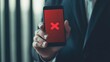 © Mitchell - A man in a suit holding a smartphone with a red screen and a large X