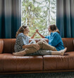 © olezzo - Lesbian couple sitting on sofa with intertwined legs holding hands and looking at each other, intimate moment at home