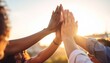 © Formasi - Diverse group celebrating success with a high five at sunset.