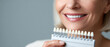 © perfectlab - Close-up of smiling woman holding dental shade guide for teeth color matching in dental care and cosmetic dentistry