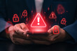 © IDOL'foto - Cyberattack warning on mobile device. hands holding smartphone with red warning alert and cyber lock symbol. mobile security breach, data hacking threat, malware or phishing attack in digital device
