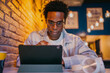 © BullRun - Young man interacting with digital tablet while sitting at a café, engaged in a digital task. A scene of focus, learning, or remote work in a relaxed, creative, tech-friendly atmosphere.