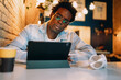 © BullRun - Man sitting at table using digital tablet with headphones beside him, reflecting immersive digital workflow, wireless tech lifestyle, and mobile-first engagement in a modern cafe environment.