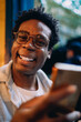 © BullRun - Playful close-up of a young man holding smartphone, smiling brightly with tablet in the background, illustrating genuine happiness and modern tech interaction.
