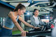 © whyframeshot - Two energetic Asian women enjoy a healthy lifestyle by running on treadmills in a modern gym, focusing on cardio training, fitness goals, and body strength while exercising with motivation, confidence