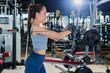 © whyframeshot - fit Asian woman working out at the gym, doing cable machine exercise wearing a gray sports top, showing strength, muscle, and determination in a modern fitness studio.