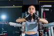 © whyframeshot - fit Asian woman working out at the gym, doing cable machine exercise wearing a gray sports top, showing strength, muscle, and determination in a modern fitness studio.