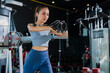 © whyframeshot - fit Asian woman working out at the gym, doing cable machine exercise wearing a gray sports top, showing strength, muscle, and determination in a modern fitness studio.