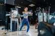 © whyframeshot - fit Asian woman working out at the gym, doing cable machine exercise wearing a gray sports top, showing strength, muscle, and determination in a modern fitness studio.