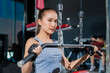 © whyframeshot - fit Asian woman working out at the gym, doing cable machine exercise wearing a gray sports top, showing strength, muscle, and determination in a modern fitness studio.