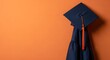 © MstSabana - Graduation cap and gown on orange background