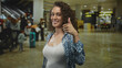 © Krakenimages.com - Woman shows thumbs up with visible breast and open smile in airport terminal; confidence travel planning.