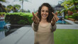 © Krakenimages.com - Woman smiling and making finger heart gesture with hands by pool in studio showing rings on fingers and wearing beige top; affection.