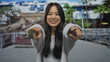 © Krakenimages.com - Young woman smiling and pointing at camera on a sunny street with modern buildings in background showcasing vibrant urban lifestyle