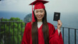 © Krakenimages.com - Woman in red graduation gown holding australian passport against seaside backdrop, symbolizing global opportunities and celebration of academic achievement by the beach.