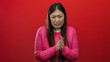 © Krakenimages.com - Woman in pink sweater against red background shows various expressions, suggesting emotions like cold and contemplation.