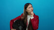 © Krakenimages.com - Woman in red jacket pondering holding helmet against blue background with thoughtful expression implying decision-making setting.