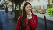 © Krakenimages.com - Woman in red jacket smiles on urban street with blurred city background highlighting vibrant, casual, and youthful style.