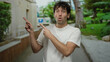 © Krakenimages.com - Man gesturing with surprise on an outdoor street with lush greenery and urban buildings in the background.