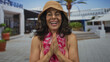 © Krakenimages.com - Middle-aged hispanic woman in a bikini with a hawaiian lei and hat smiling outdoors in a sunny setting with a relaxed summer vibe.