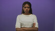 © Krakenimages.com - Black woman in a striped top with braided hair, arms crossed and eyes shut while frowning in a purple studio setting; disapproval tension resolve.