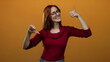 © Krakenimages.com - Woman making thumbs up down gestures against orange background expressing mixed emotions in a red sweater with glasses showing both approval and disapproval.