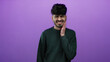 © Krakenimages.com - Man with toothache expression against a purple background, wearing a green sweater, showing discomfort and pain, isolated and posing for a portrait.