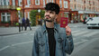 © Krakenimages.com - Man holding french passport on city street with urban background, showcasing architecture, while dressed in denim, exuding confidence and style, photographed outdoors.