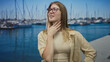© Krakenimages.com - Blonde woman wearing glasses pinches nose beside boats on sunlit street pier over blue water; disgust.