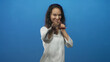 © Krakenimages.com - Young hispanic woman smiling points finger toward camera with outstretched hands in blue studio; playful joy.