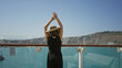 © Krakenimages.com - Woman raising arms overhead beside glass railing on cruise ship deck building under clear sky, wearing sunhat and black jumpsuit; serenity.