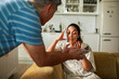© Marko Geber - Older man shows smartphone to frustrated young woman in home kitchen