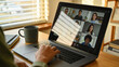 © SHOTPRIME STUDIO - Remote team meeting with diverse colleagues on laptop screen in cozy home office. Hand on keyboard shows active participation during video conference for work collaboration and communication.