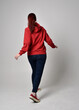 © faestock - full length figure of female model wearing  basic contemporary casual clothing, red hoodie jumper, skinny jeans, sneakers. standing pose walking away back view,  isolated white studio background.