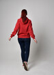 © faestock - full length figure of female model wearing  basic contemporary casual clothing, red hoodie jumper, skinny jeans, sneakers. standing pose walking away back view,  isolated white studio background.