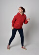 © faestock - full length figure of female model wearing  basic contemporary casual clothing, red hoodie jumper, skinny jeans, sneakers. walking action pose, isolated white studio background.
