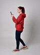 © faestock - full length figure of female model wearing  basic contemporary casual clothing, red hoodie jumper, skinny jeans, sneakers. standing walking pose holding cell phone mobile,  isolated white studio backg