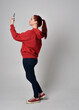 © faestock - full length figure of female model wearing  basic contemporary casual clothing, red hoodie jumper, skinny jeans, sneakers. standing walking pose holding cell phone mobile,  isolated white studio backg