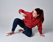 © faestock - full length figure of female model wearing  basic contemporary casual clothing, red hoodie jumper, skinny jeans, sneakers.  kneeling on floor  isolated white studio background.