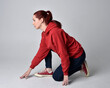 © faestock - full length figure of female model wearing  basic contemporary casual clothing, red hoodie jumper, skinny jeans, sneakers.  kneeling on floor  isolated white studio background.