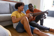 © wavebreak3 - African american friends lying at home holding controllers gaming